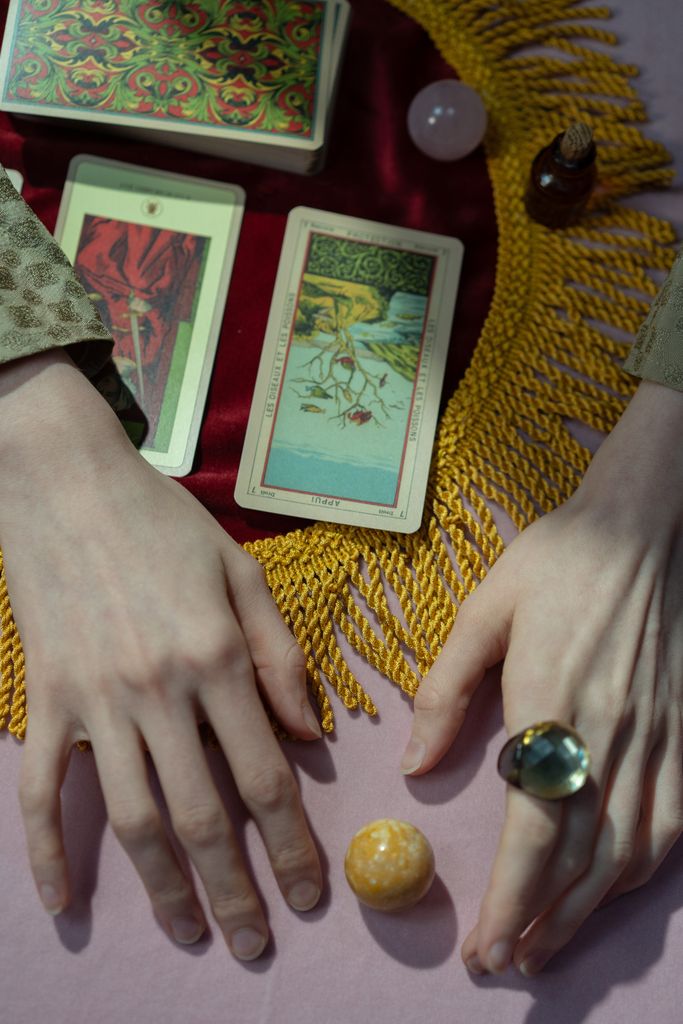Serene scene of hands poised over tarot cards, evoking mystery and spirituality.